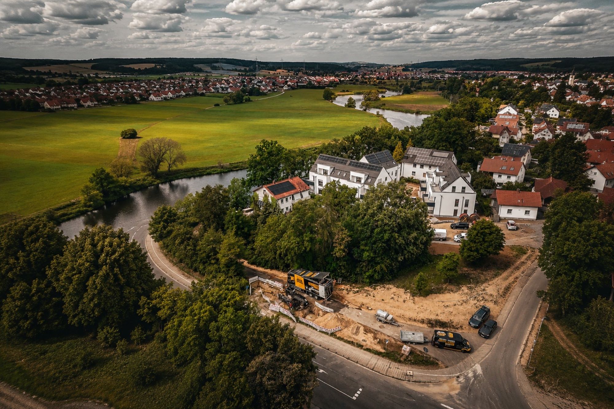 Luftbild: Baustelle von Bohrtechnik Schulze am Ortsrand, daneben ein Fluss